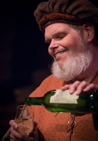 Production pic of Falstaff pouring a glass of wine